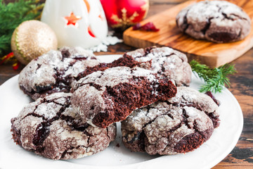 Cracked chocolate cookies with cranberries on white plate on wooden rustic table. Christmas decoration, close-up