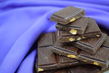 Dark chocolate with nut on blue background.