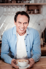 Joyful pleasant barista serving coffee