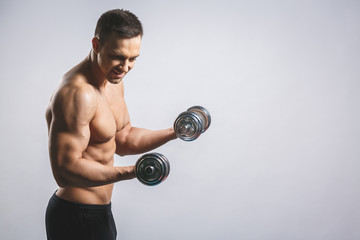 Fototapeta na wymiar Muscular bodybuilder guy doing exercises with dumbbell over white background.
