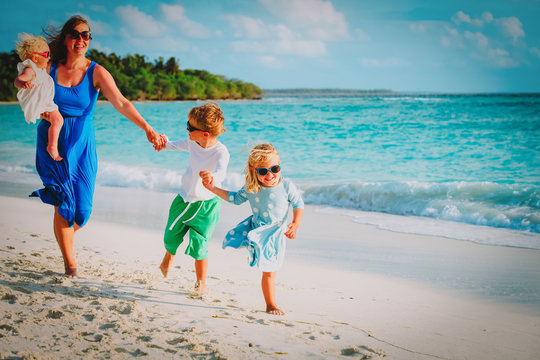 mother with kids play run on tropical beach