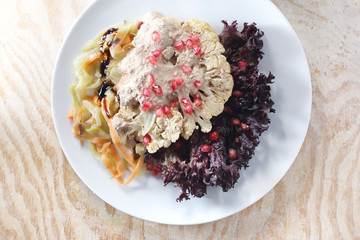 Kalafior w sosie jogurtowym.  Pieczony kalafior z sosem jogurtowym podany z owocem granatu. © foodandcook