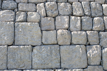 Stone wall is made from cubic hard grey rocks. 