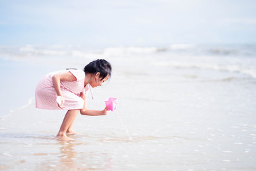 Asian child girl playing with toys on the beach