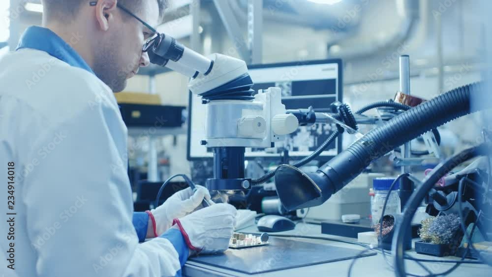 Poster electronics factory worker in white work coat is soldering a printed circuit board through a digital