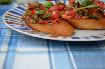 Traditional italian bruschetta with cherry tomatoes, cream cheese, basil leaves, capers and balsamic vinegar on plate. Close up view