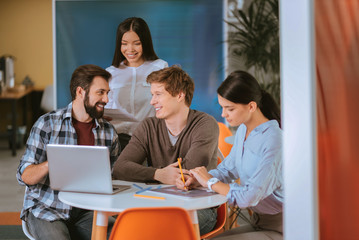 Fototapeta premium Merry four colleagues developing business plan