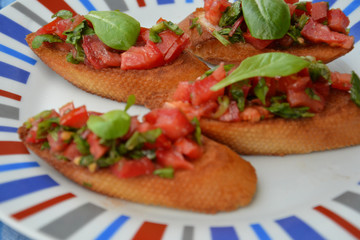 Traditional italian bruschetta with cherry tomatoes, cream cheese, basil leaves, capers and balsamic vinegar on plate. Close up view