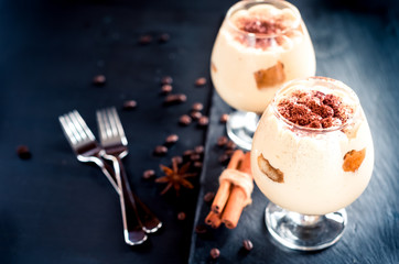 tiramisu in a glass decorated with coffee beans on a dark background