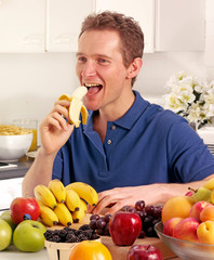 MAN IN KITCHEN WITH FRUIT EATING BANANA