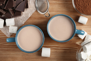 two cups of cocoa, marshmallows and pieces of chocolate on the table