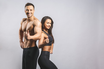 Athletic man and woman isolated over white background. Personal fitness instructor. Personal training. Thumbs up.