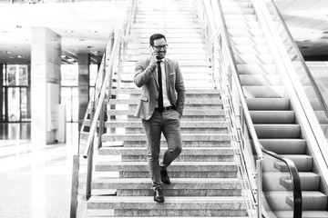 Smiling businessman walking down the stairs and talking on the phone.