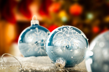 Blue baubles on wooden table with copy space and blurred interior with Christmas decorations, Christmas tree and fireplace background.