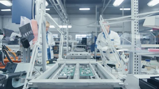 Time Lapse of Electronics Factory Workers Assembling Circuit Boards by Hand While it Moves on the Assembly Line. High Tech Factory Facility.