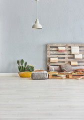 Decorative grey bed room pallet headboard books and grey puff.