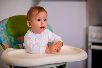 Child Feeding. Happy kid sitting on the highchair..