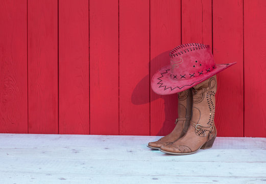Cowboy women's boots, hat on a red wooden background