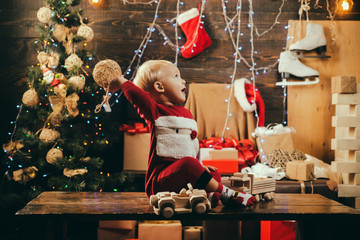 Christmas childhood. Merry Christmas and Happy New Year. Cute little child on Christmas tree background. The child boy laughing and enjoying the gift. Christmas toys.