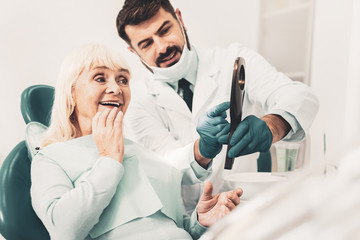 Dentist showing new denture to her client