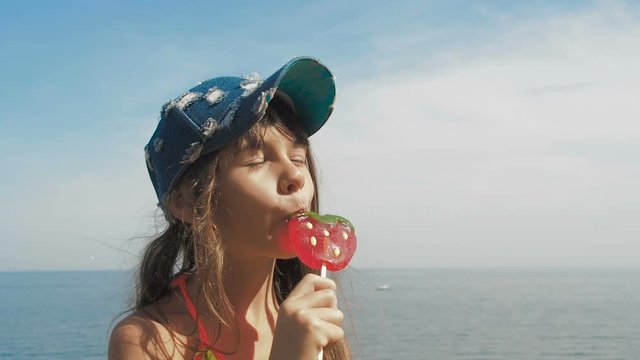 Happy child with a lollipop on the beach.