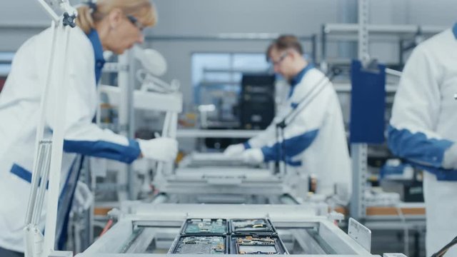 Time Lapse of Electronics Factory Workers Assembling Smartphone Circuit Boards by Hand While they Move on the Assembly Line. High Tech Factory Facility.