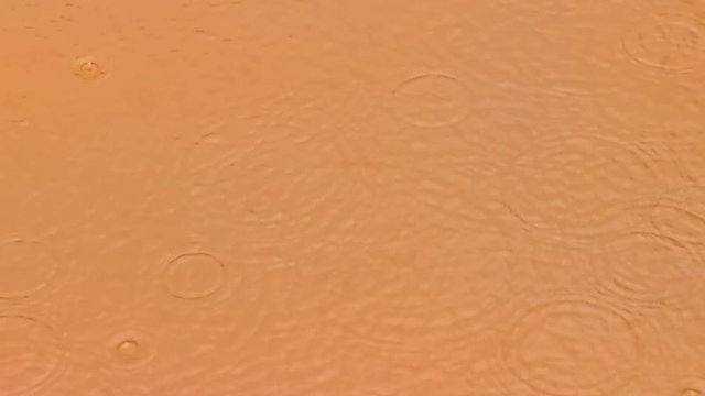 Gotas de lluvia salpicando en un charco de agua embarrada 