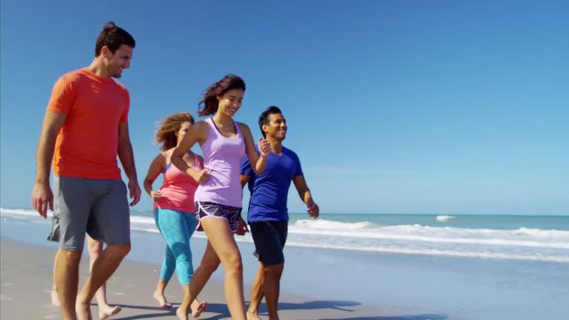 Multi ethnic males and females enjoying walking on their beach vacation