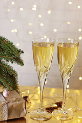 Two glasses of champagne are on the table next to the Christmas and New Year presents under the Christmas tree