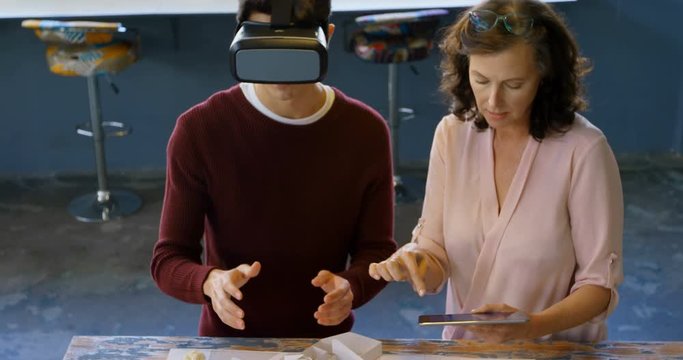 Executives using digital tablet and virtual reality headset while discussing over architectural mode
