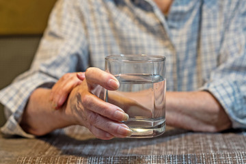 old women's hands holding a glass of water