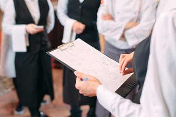 restaurant manager and his staff in kitchen. interacting to head chef in commercial kitchen.