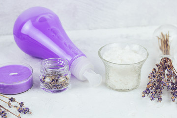 Obraz na płótnie Canvas spa set with sea salt, dry lavender flower petals, candles and lavender liquid soap on a white shabby table