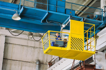 The girl working in the cab of a crane. Heavy industry, metal factory.