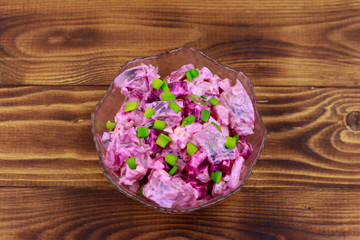 Tasty salad with herring, beetroot, eggs, onion and mayonnaise on wooden table. Top view
