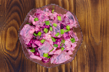 Tasty salad with herring, beetroot, eggs, onion and mayonnaise on wooden table. Top view