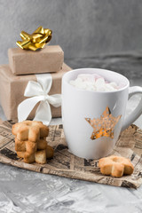 Obraz na płótnie Canvas winter hot sweet drink cups with gift boxes and cookies on a shabby gray concrete background