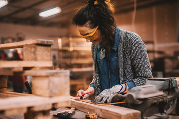 Female carpenter working in workshop. Female doing male's work concept. - obrazy, fototapety, plakaty