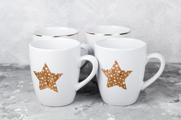 cute stylish white ceramic cups set on a gray shabby background