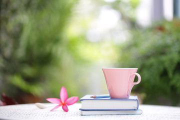 Pastel pink cup with flower and books at outdoor 