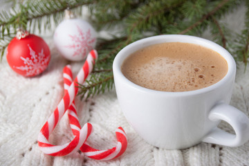 Coffee in a white cup with candy and Christmas balls