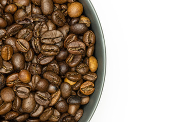 Closeup of lot of whole dark brown coffee beans sweet arabica variety in a grey ceramic bowl flatlay isolated on white background