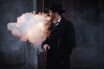 man in hat vaping electronic mod. man in classic hat and coat