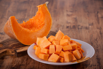 Slices of pumpkin in a plate on an old wooden table
