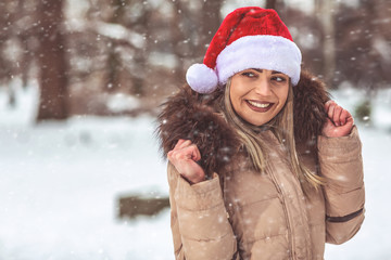 Obraz premium Christmas time – beautiful woman with Santa hat winter snow day .