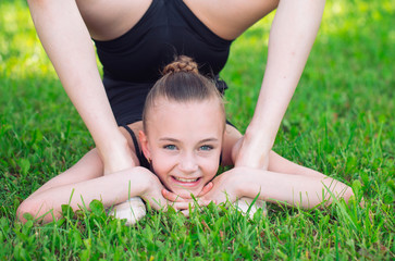 Naklejka na ściany i meble Beautiful little girl doing gymnastics on the grass on a sunny day