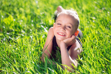 cute happy little girl lying on the grass