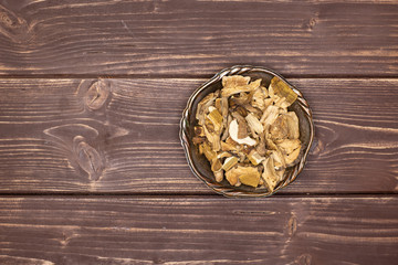 Obraz na płótnie Canvas Lot of slices of edible dry brown mushroom boletus edulis variety in old iron bowl flatlay on brown wood