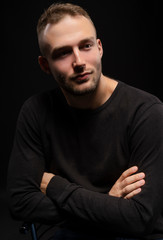 Closeup portrait of a stylish young man with a stubble on his face wearing a black jacket. Fashionable, advertising and commercial design.