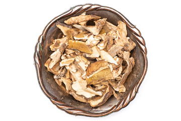 Lot of slices of dry brown mushroom boletus edulis variety in old iron bowl flatlay isolated on white background